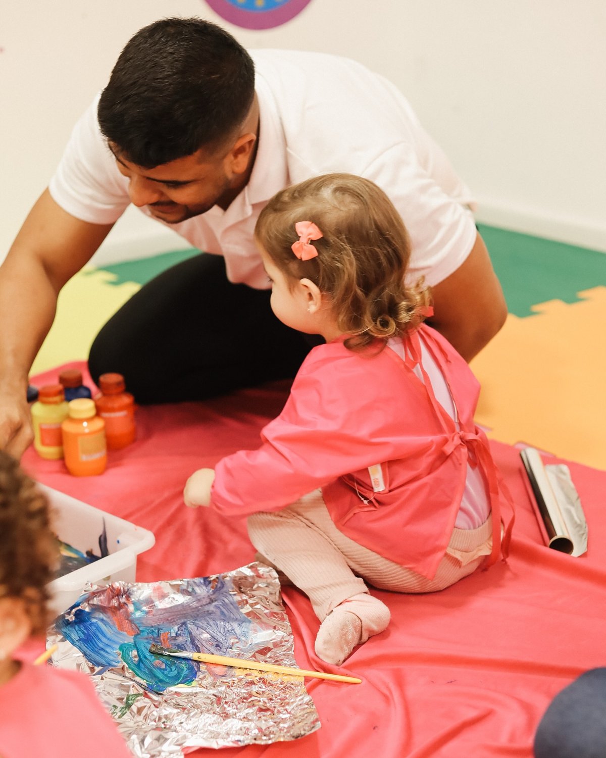 Professor acompanhando uma criança durante atividade de pintura sensorial na Baby Gym Volta Redonda