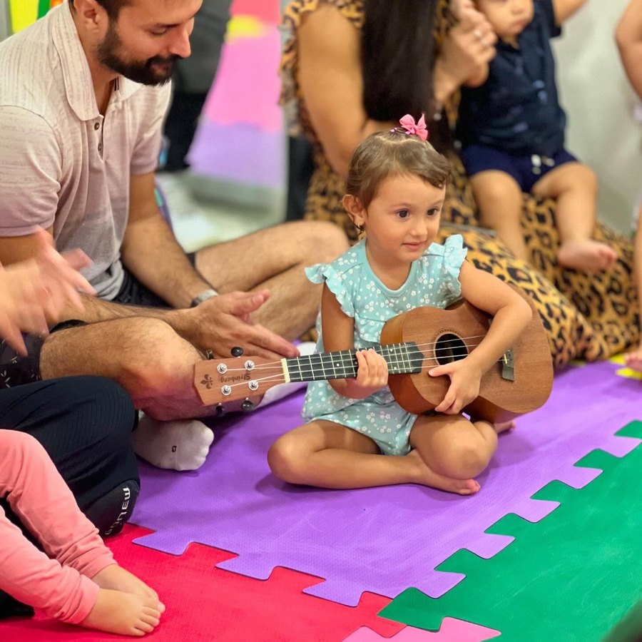 Menina tocando ukulele durante a aula de musicalização na Baby Gym Volta Redonda