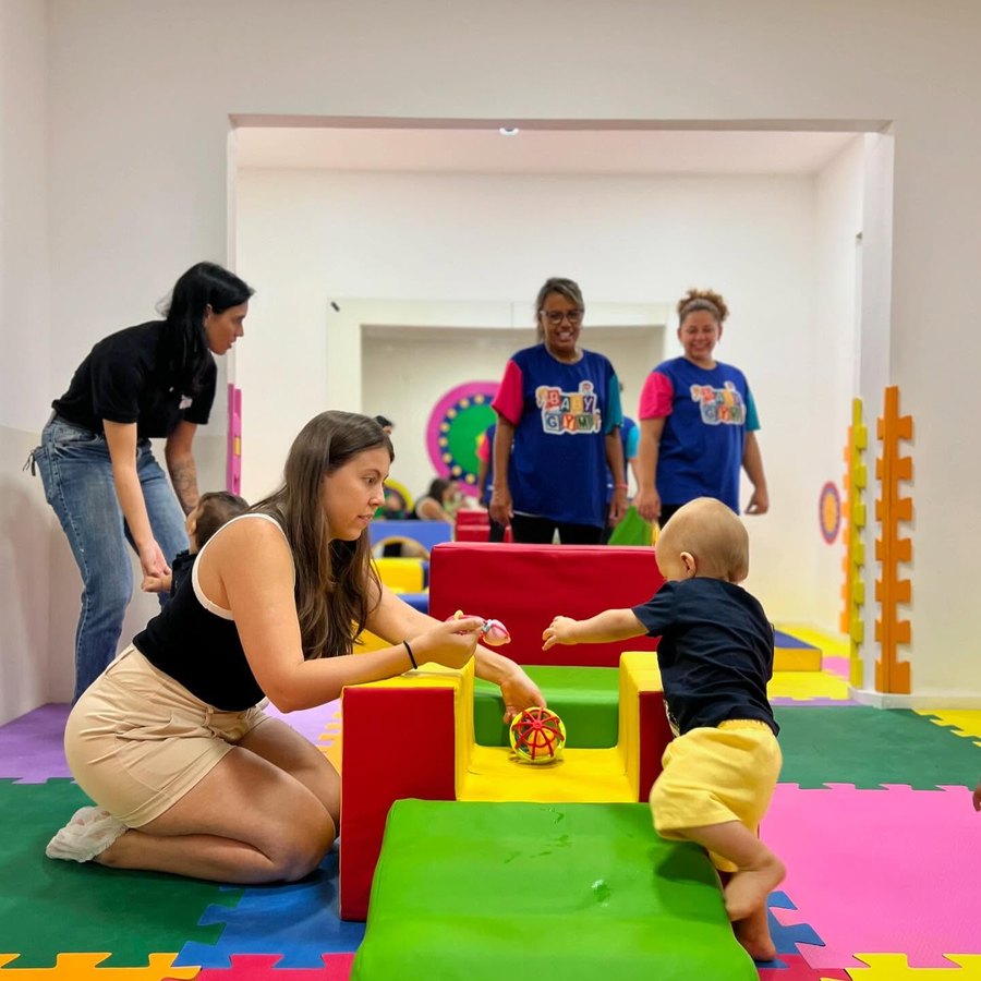 Bebê subindo em circuito de espuma com apoio da mãe e da equipe Baby Gym